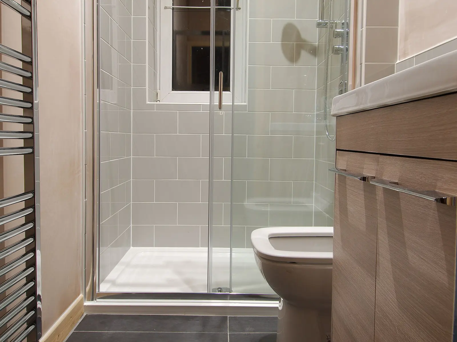 Después: baño terminado con ducha de vidrio y revestimiento claro