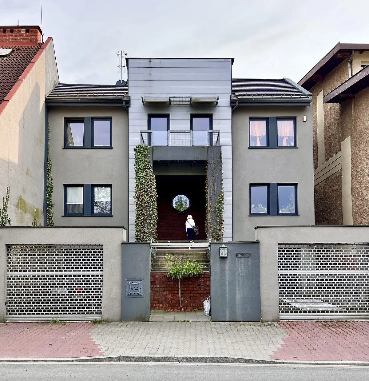 Fachada de vivienda moderna gris con aberturas negras