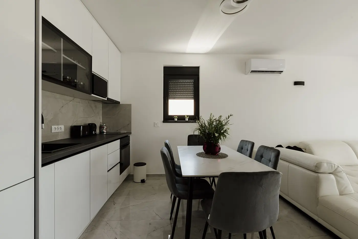 Cocina comedor integrada con muebles blancos y mesada negra